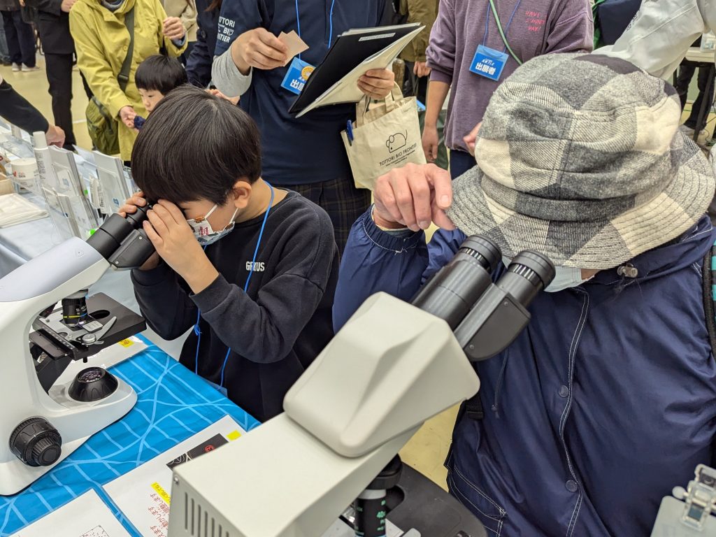 顕微鏡をのぞく来場者